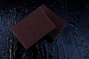 Melamine sponge on a black wet background. Beautiful drops of water around a melamine sponge. photo