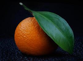 Ripe juicy tangerine on a black background with water drops. photo