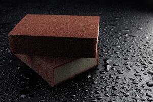 melamina esponja en un negro mojado antecedentes. hermosa gotas de agua alrededor un melamina esponja. foto