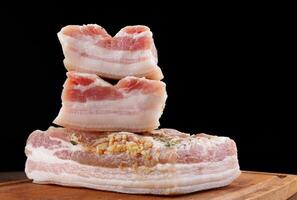 Appetizing salty lard with layers of meat with garlic and herbs. Delicious lard on a wooden cutting board. photo