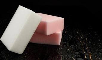 Melamine sponge on a black wet background. Beautiful drops of water around a melamine sponge. photo