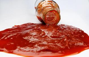 Tomato sauce . Glass bottle with ketchup. Ketchup is pouring out of the neck of a glass bottle. photo