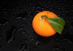 Ripe juicy tangerine on a black background with water drops. photo