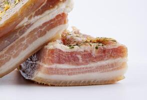 Appetizing salty lard with layers of meat with garlic and herbs. Two pieces of salted lard on a white background. photo