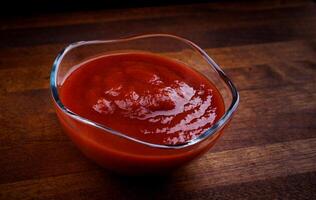 salsa de tomate en un vaso taza en un de madera tablero. foto