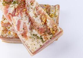 Appetizing salty lard with layers of meat with garlic and herbs. Two pieces of salted lard on a white background. photo