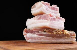 Appetizing salty lard with layers of meat with garlic and herbs. Delicious lard on a wooden cutting board. photo