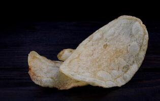 Potato chips on a dark background. Chips on a wooden board photo