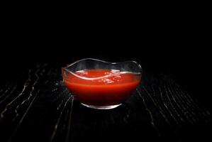 salsa de tomate en un vaso taza en un negro antecedentes. foto