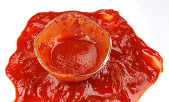 Tomato sauce . Glass cup with remaining ketchup and ketchup spilled around it. photo