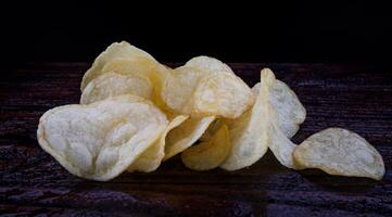 patata papas fritas en un oscuro antecedentes. papas fritas en un de madera tablero foto