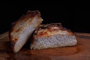 Roasted pork entrecote cut into pieces on a wooden cutting board. Grilled pork entrecote. Pork steak. photo