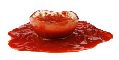 tomate salsa . vaso taza con salsa de tomate y un charco de salsa de tomate derramado alrededor eso aislado en un blanco antecedentes. foto