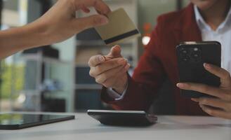 mano participación crédito tarjeta y utilizando ordenador portátil. mujer de negocios o empresario trabajando desde hogar. en línea compras, comercio electrónico, Internet bancario, gasto dinero, trabajo desde hogar concepto foto