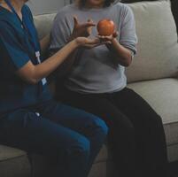 Happy young female nurse provide care medical service help support smiling old grandma at homecare medical visit, lady carer doctor give empathy encourage retired patient sit on sofa at home hospital photo