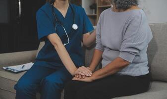 Female caregiver doing regular check-up of senior woman in her home. photo