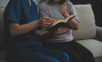 Happy young female nurse provide care medical service help support smiling old grandma at homecare medical visit, lady carer doctor give empathy encourage retired patient sit on sofa at home hospital photo