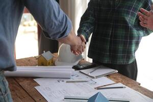 ingeniero y contratista unirse manos después firma contrato, ellos son teniendo un moderno edificio proyecto juntos. exitoso cooperación equipo concepto foto