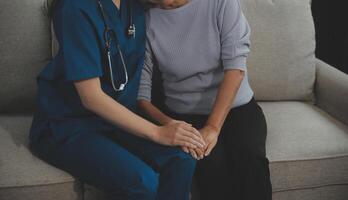 Female caregiver doing regular check-up of senior woman in her home. photo