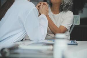 African female doctor hold hand of caucasian woman patient give comfort, express health care sympathy, medical help trust support encourage reassure infertile patient at medical visit, closeup view. photo