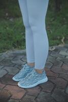 Young female workout before fitness training session at the park. Healthy young woman warming up outdoors. She is stretching her arms and looking away,hi key. photo