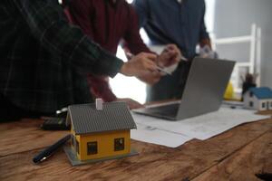 ingenieros son consultante el equipo a diseño un arquitectónico estructura para clientela con planos y edificio modelos a trabajo a oficina. foto