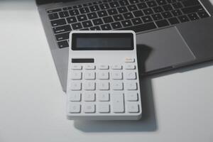 plano poner, parte superior ver oficina mesa escritorio. espacio de trabajo con calculadora, bolígrafo, computadora portátil en blanco fondo.copiar espacio para texto, vacío blanco a palabra.negocio finanzas,educación tecnología.trabajo desde hogar. foto