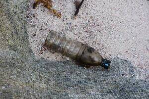 sucio el plastico botella en un arena playa foto