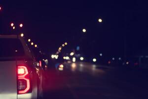 Abstract and blurred view of picture car in city at night. Turn on brake light with lighting of pole beside road. photo