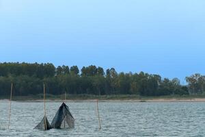 Lanscape view of river with nets catch fish in the water. Occupation that earns a living from fishing. Environment of river and forest in the evening. photo