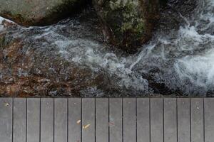 Wooden walkway in the forest with waterfall and rocks background. empty space to present something about nature. photo