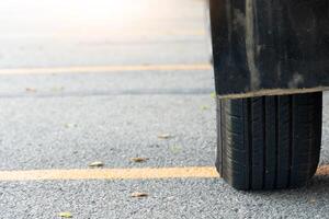 Close of used car tires on asphalt road with sun light in the morning time. With yellow line across the floor. photo