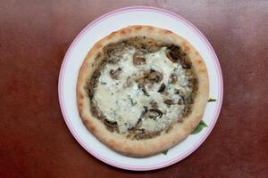 Above view of Pizza topped with truffle mushrooms and dense cheese. Arrange on a round plate. and placed on a red background photo