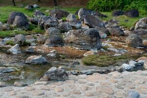 Rocks protruding above the surface of the water in chaeson Hot Spring. with a thin layer of steam. At Chae Son National Park Thailand. photo