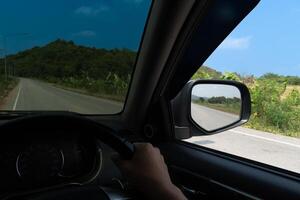 ver desde el dentro de un coche. ver desde el conductor asiento. conducción en el asfalto la carretera con naturaleza de árbol y montaña junto a la carretera. debajo azul cielo en el día tiempo. foto