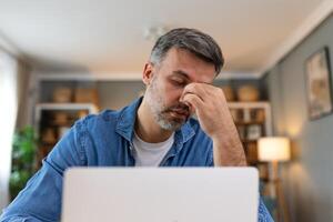 empresario oficina trabajando participación dolorido cabeza dolor desde escritorio trabajando y sentado todas día utilizando ordenador portátil computadora o cuaderno sufrimiento dolor de cabeza enfermo trabajador exceso de trabajo concepto foto