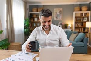 Shot of a businessman on a call while sitting at his desk. Cropped shot of an attractive man using his laptop to make a call at home photo