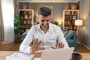 Shot of a businessman on a call while sitting at his desk. Cropped shot of an attractive man using his laptop to make a call at home photo