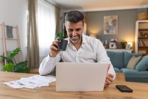 Shot of a businessman on a call while sitting at his desk. Cropped shot of an attractive man using his laptop to make a call at home photo