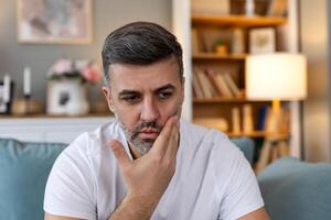 Tooth Pain And Dentistry. Young Man Suffering From Terrible Strong Teeth Pain, Touching Cheek With Hand. Feeling Painful Toothache. Dental Care And Health Concept. High Resolution photo