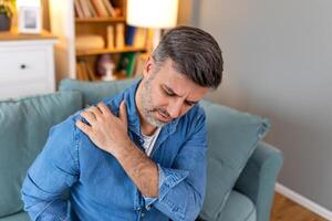 Young man with shoulder pain. male holding his painful shoulder. man hand holding his shoulder suffering from shoulder pain suffering from pain in hand at home. photo