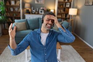 Excited biracial male call center agent in headset have fun laugh working on computer online, overjoyed man busy studying or watching funny training webinar on computer gadget photo