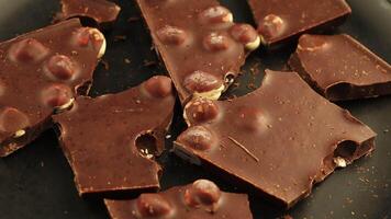 chocolate con nueces en negro. oscuro chocolate piezas de cerca. video
