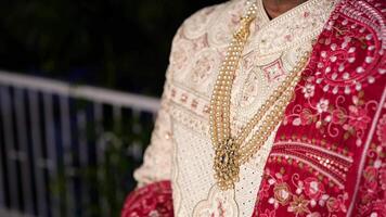 Indian groom in close-up, wearing a sherwani with intricate designs with a pearl necklace video