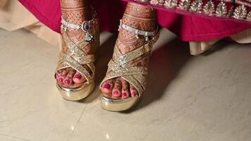 Beautiful bride showing her bridal sandals with silver payal on her legs, with bridal Mehndi henna design on her legs , wearing a beautiful bright lehenga video