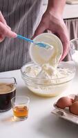 hombre vistiendo delantal Cocinando Tiramisu a cocina. Tiramisu Cocinando proceso, mezcla mascarpone y azotado huevos crema en bol, lento movimiento video
