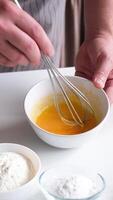 Whipping eggs in a ceramic bowl. Egg yolks and egg whites mixed with sugar. slow motion video