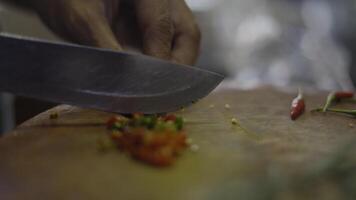 hand- snijden Chili peper met mes Aan hakken bord. video