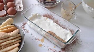 uomo indossare grembiule cucinando Tiramisù a cucina. Tiramisù cucinando processi, mettendo biscotti in caffè video