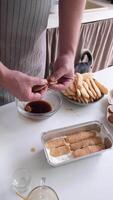 hombre vistiendo delantal Cocinando Tiramisu a cocina. Tiramisu Cocinando proceso, poniendo galletas dentro café video